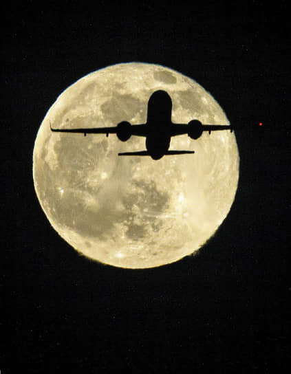 Жанровая фотография. Самолет во время полета на фоне полной луны.