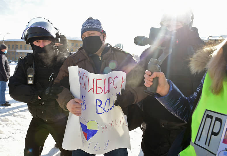 Сотрудники правоохранительных органов задерживают мужчину с плакатом, пришедшего на несогласованную акцию 