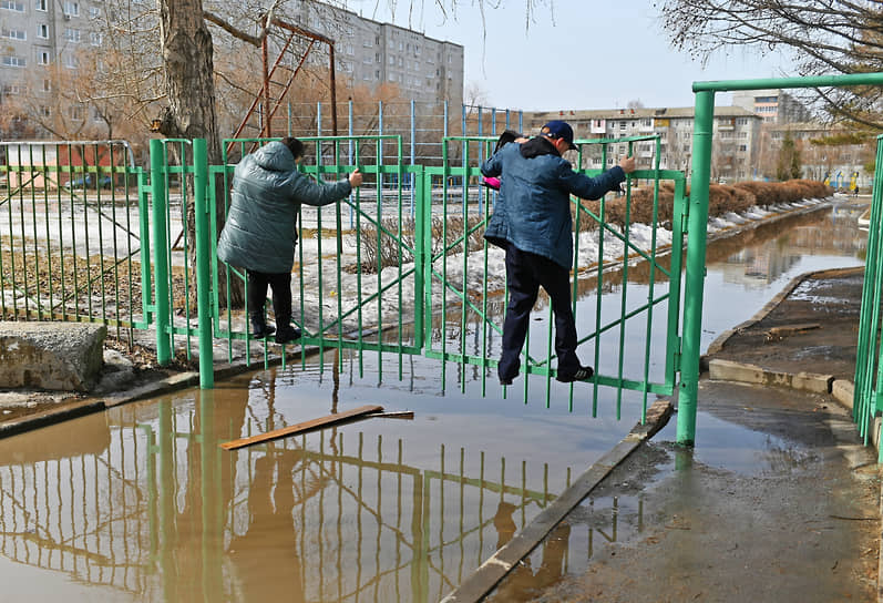 Люди переходят затопленную дорогу в Омске