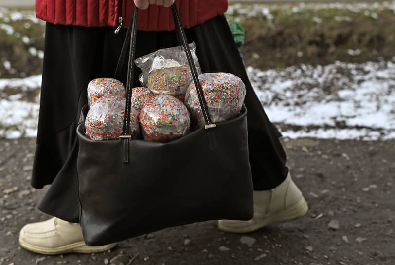 Женщина несет в сумке пасхальные куличи в Омске
