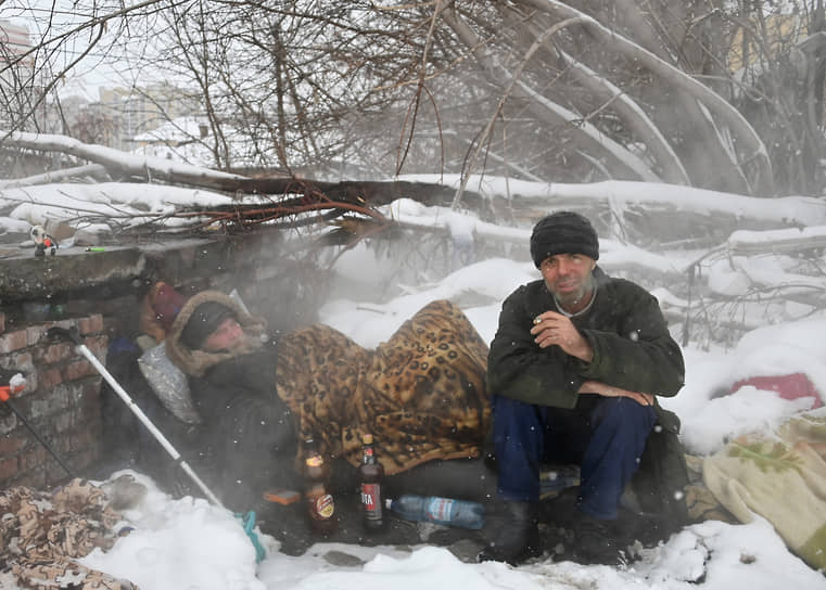 Бездомные мужчины на теплотрассе в Омске во время снегопада