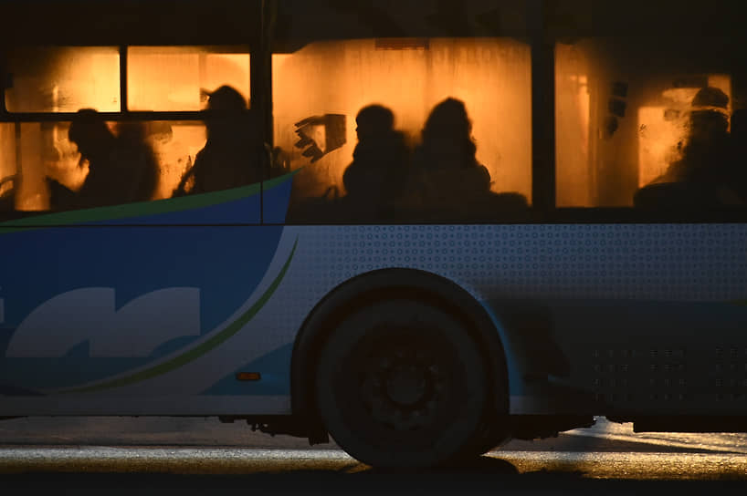 Пассажиры в автобусе общественного транспорта на Юбилейном мосту через реку Омь во время захода солнца в Омске