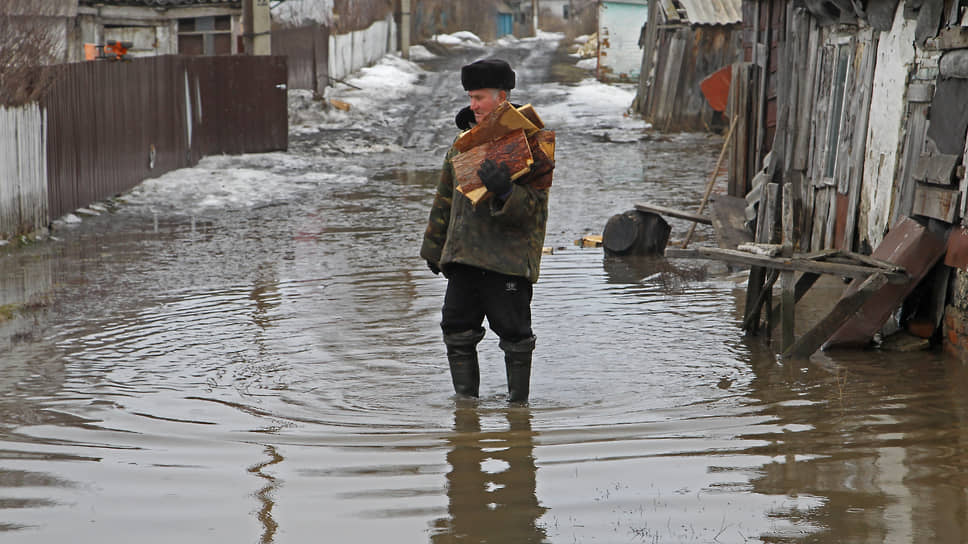 Мужчина несет охапку дров на затопленной улице частного сектора в Барнауле 