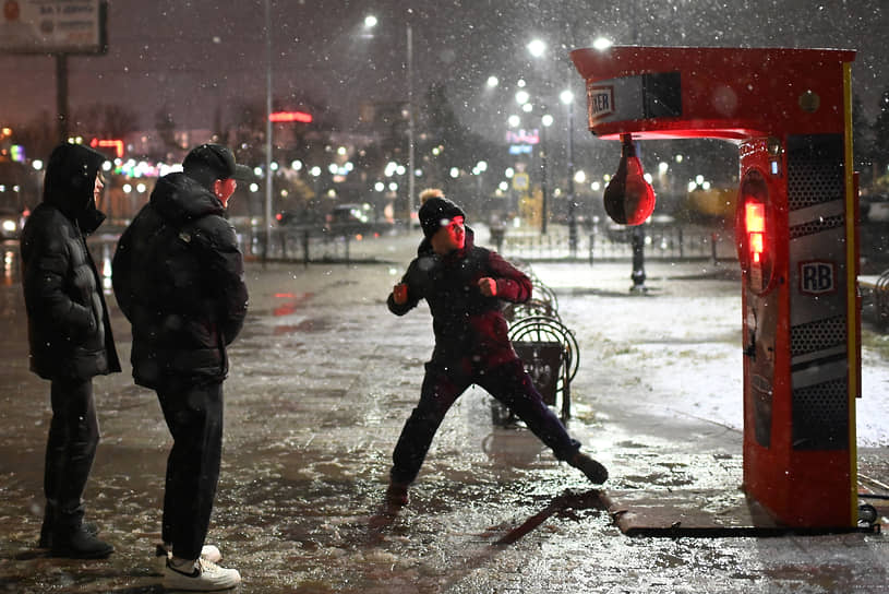 Виды Омска во время снегопада. Молодые люди возле уличной боксерской груши на городской спортивной площадке