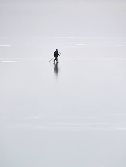 Замерзшее Новосибирское водохранилище (Обское море). Рыбак идет по льду водохранилища