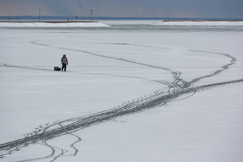 Рыбак во время зимней рыбалки на замерзшем Новосибирском водохранилище