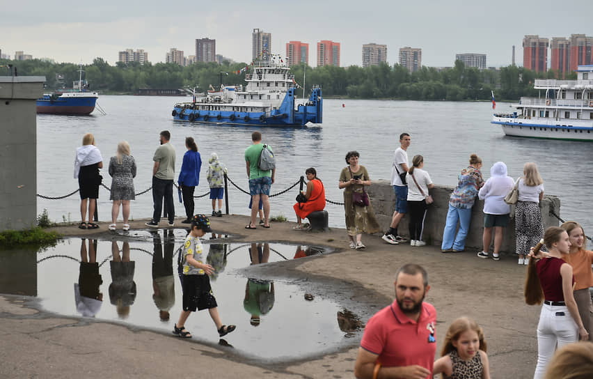 Праздничные мероприятия в честь Дня работников морского и речного флота в Красноярске. Парад судов в акватории Енисея напротив Речного вокзала. Зрители на набережной во время парада