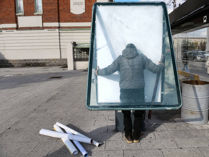 Сотрудник службы обслуживания рекламных конструкций во время замены плаката в Новосибирске