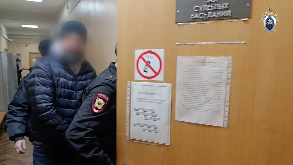Один из задержанных под конвоем заходит в зал судебных заседаний