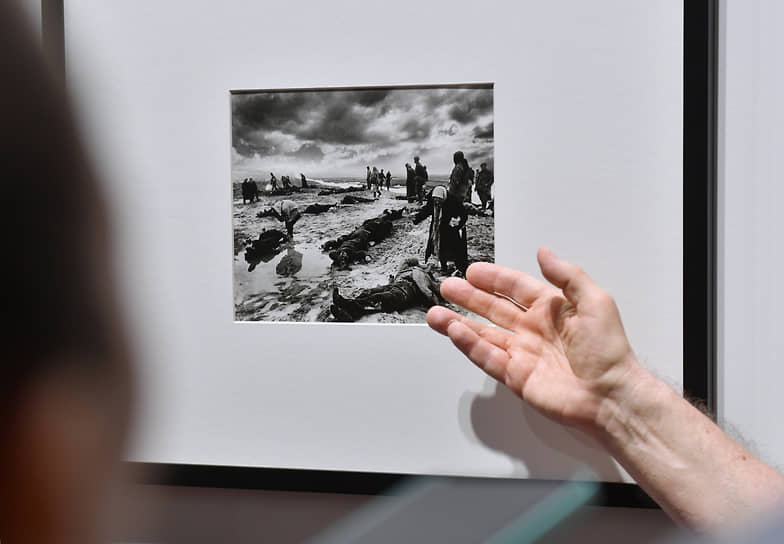 Посетители на выставке смотрят на фотографию Дмитрия Бальтерманца: «Горе. Керчь». 1942 год. Желатиносеребряный отпечаток, фотомонтаж