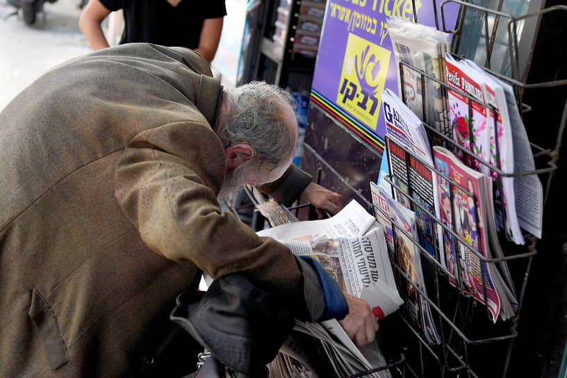 Мужчина читает новости в газете рядом с магазином прессы