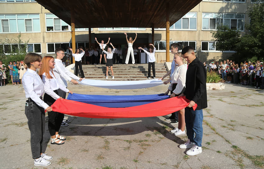 Во дворе школьники показывают выступление с флагом