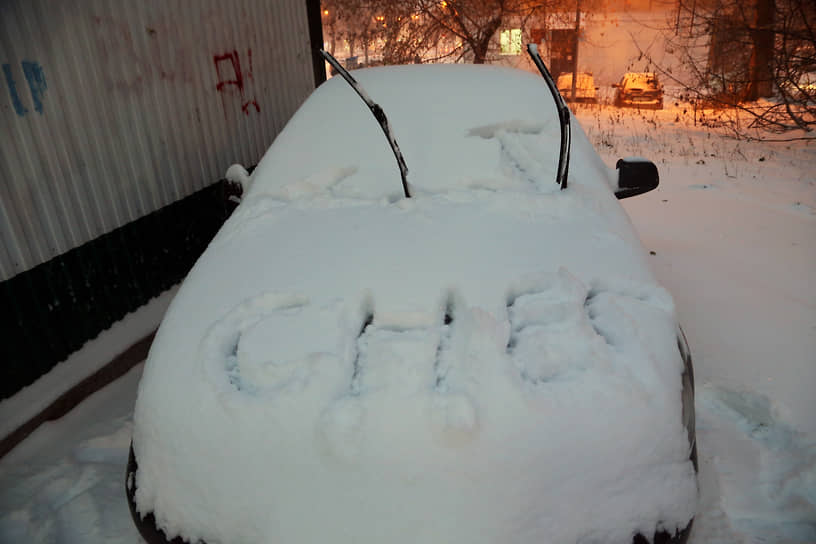 Засыпанный снегом автомобиль во дворе
