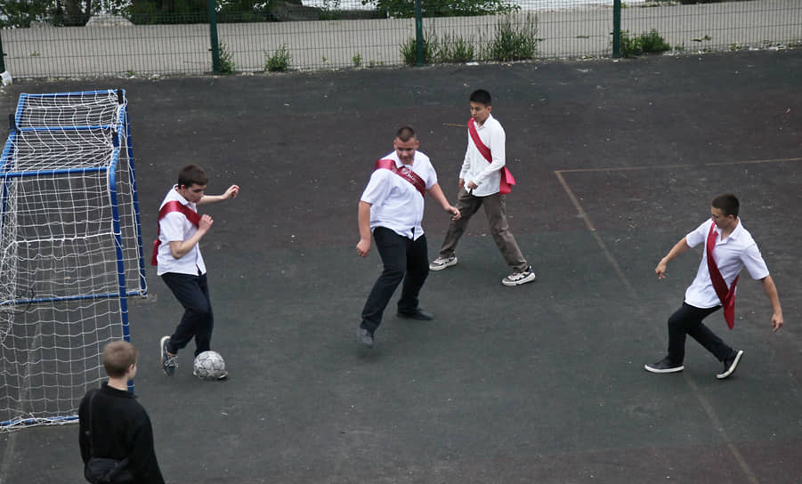 Выпускники играют в футбол на спортплощадке