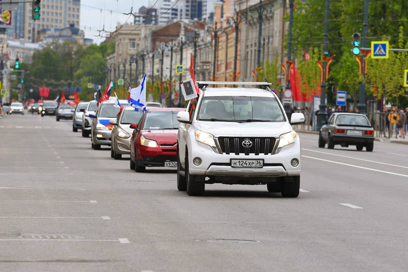 Колонна автомобилей с флагами во время праздничного автопробега по улицам города