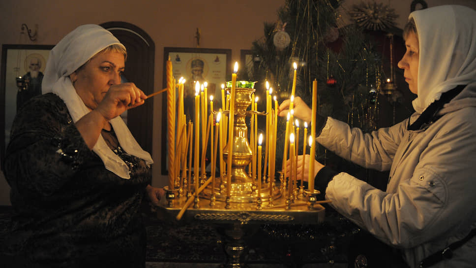 Женщины ставят свечи во время богослужения в рождественскую ночь в храме Рождества Христова (частично разрушенный и восстанавливаемый православный храм в Воронеже)