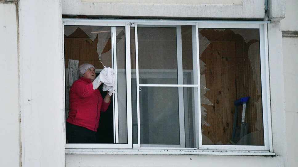 Женщина убирает остатки разбитого окна после атаки в Воронеже БПЛА на улице Тепличная