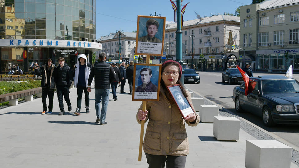 Женщина с портретами родственников, участников войны, на улице города