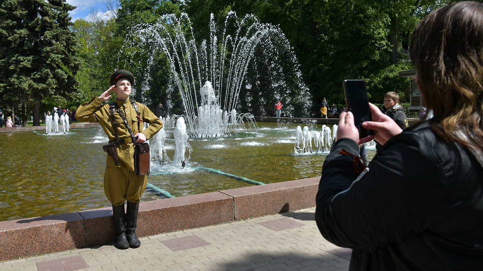 Молодой человек в форме солдата времен Великой Отечественной войны фотографируется у фонтана в Кольцовском сквере