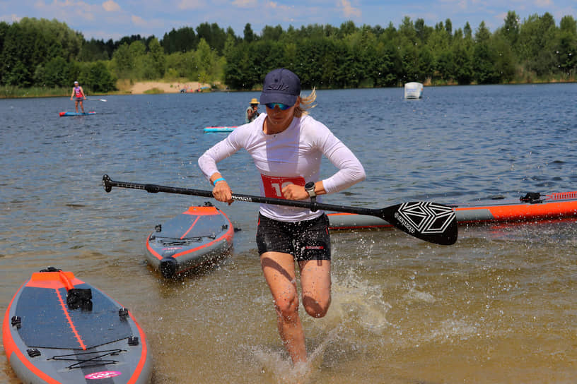 Спортсменка Ольга Курносова выбегает на берег, финишируя в женском спринте