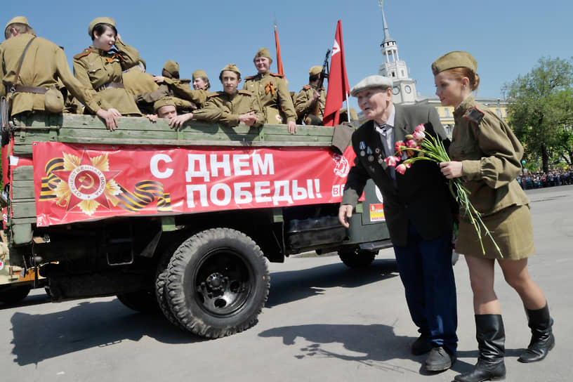 Участники реконструкции в форме солдат советской армии помогают ветерану Великой Отечественной войны пройти на гостевую трибуну перед началом парада на площади Ленина в Воронеже. 2010 год