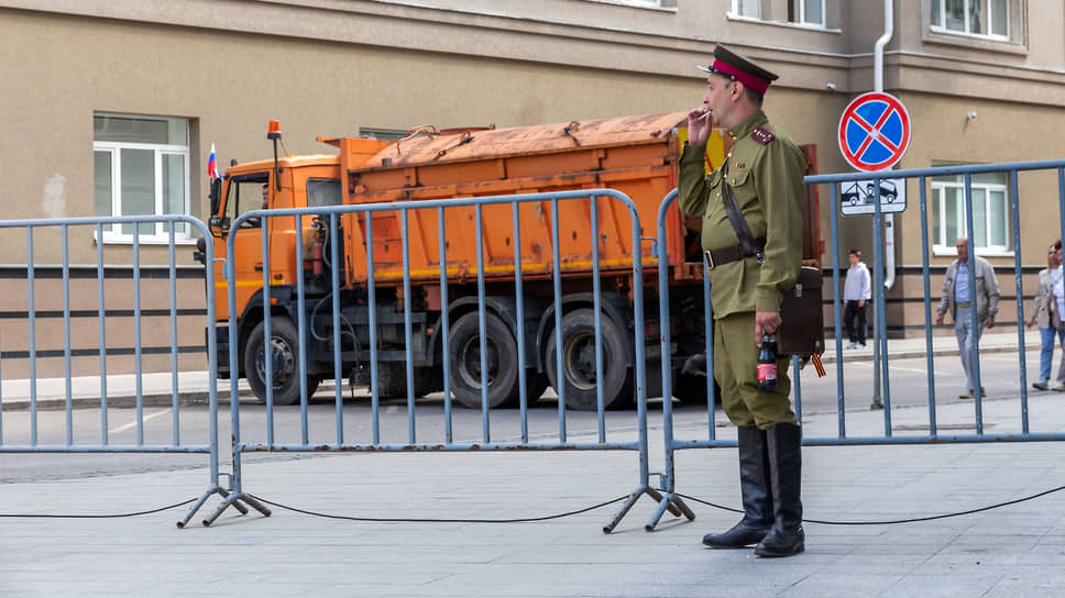 Мужчина в военной форме времен Великой Отечественной войны курит возле ограждения