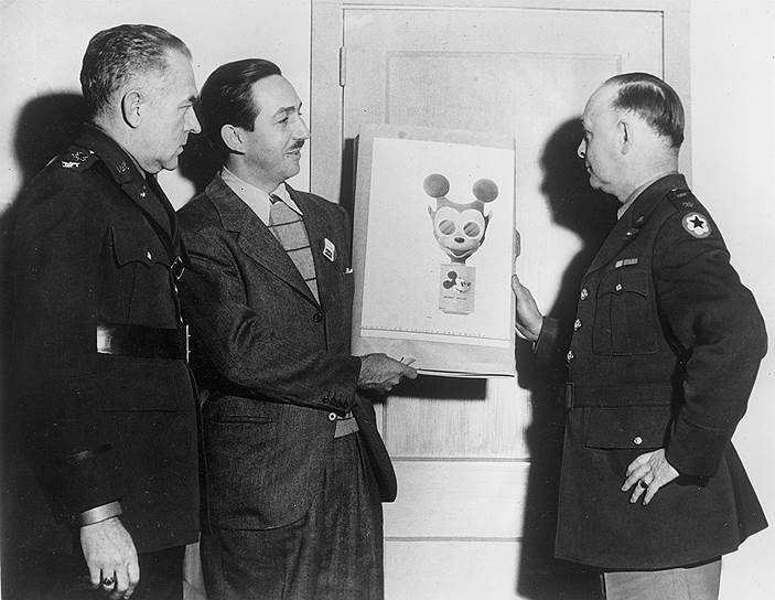Уолт Дисней (в центре) демонстрирует военным эскиз противогаза в форме Микки-Мауса, 1942